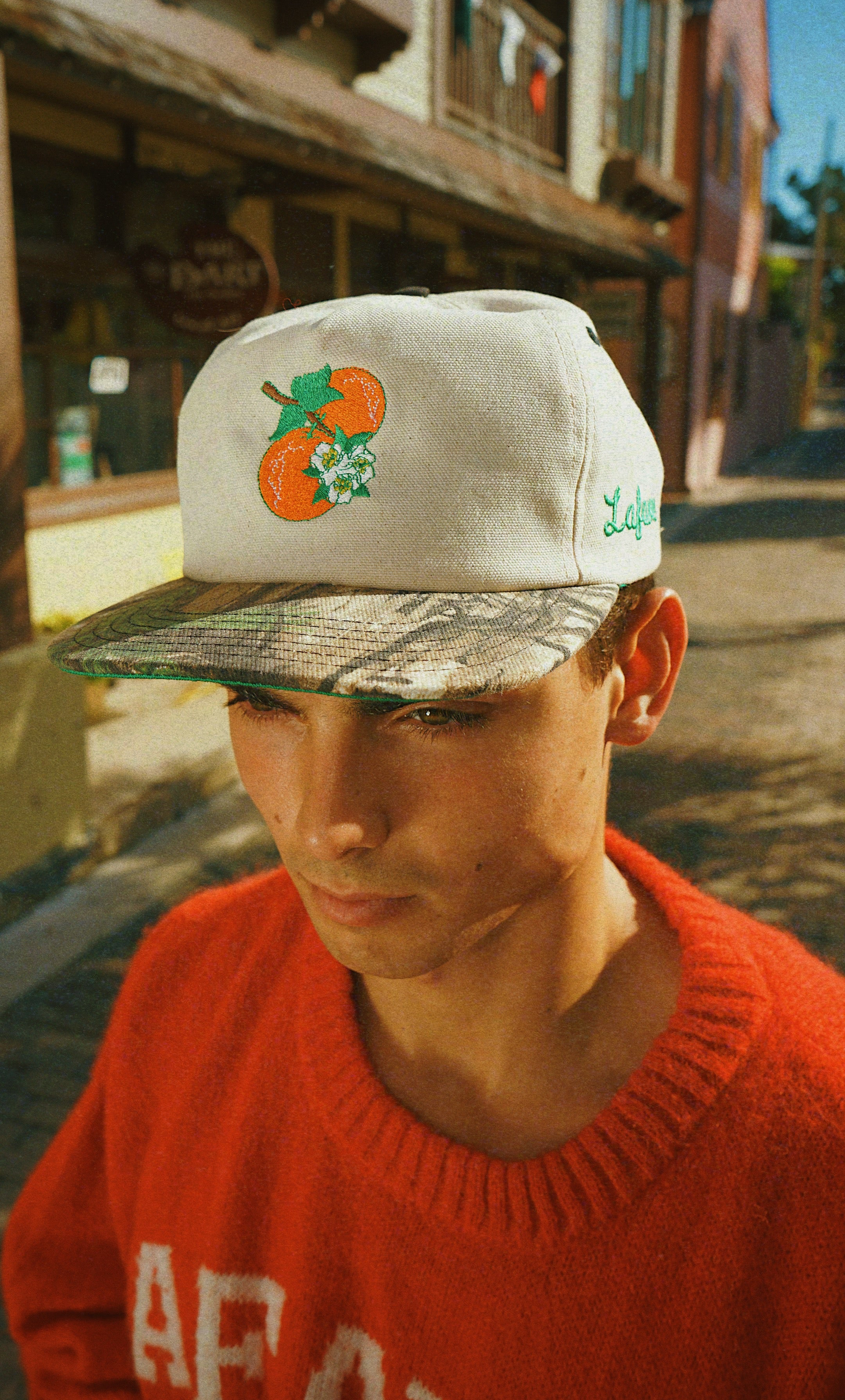 Person wearing a cap with an orange design in an urban setting