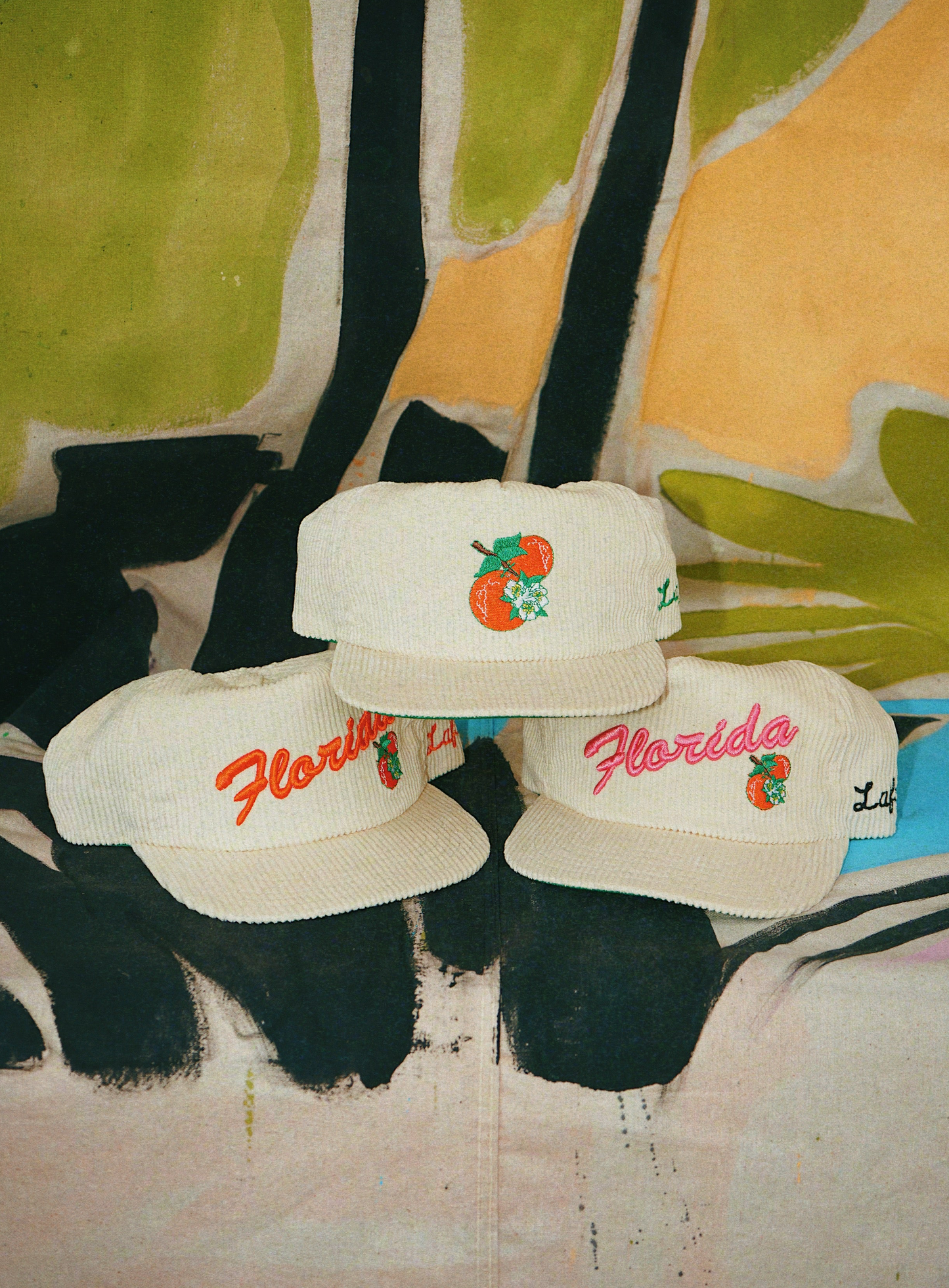 Three white caps with 'Florida' and peach designs on a colorful background