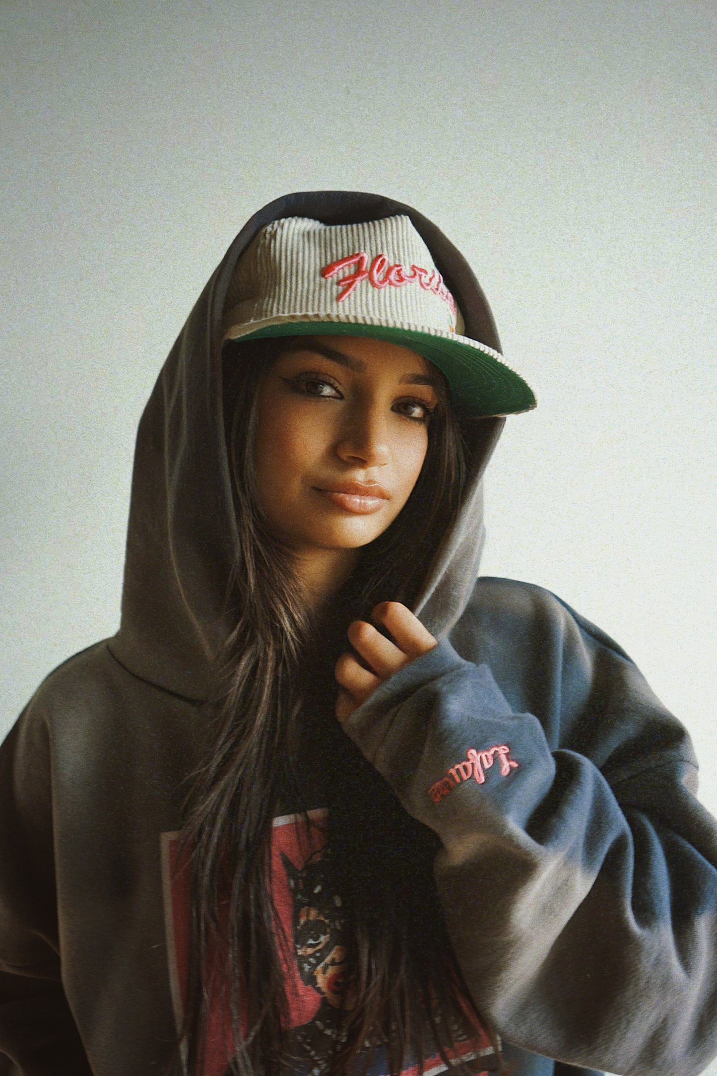 Person wearing a hoodie and cap with visible branding against a plain background