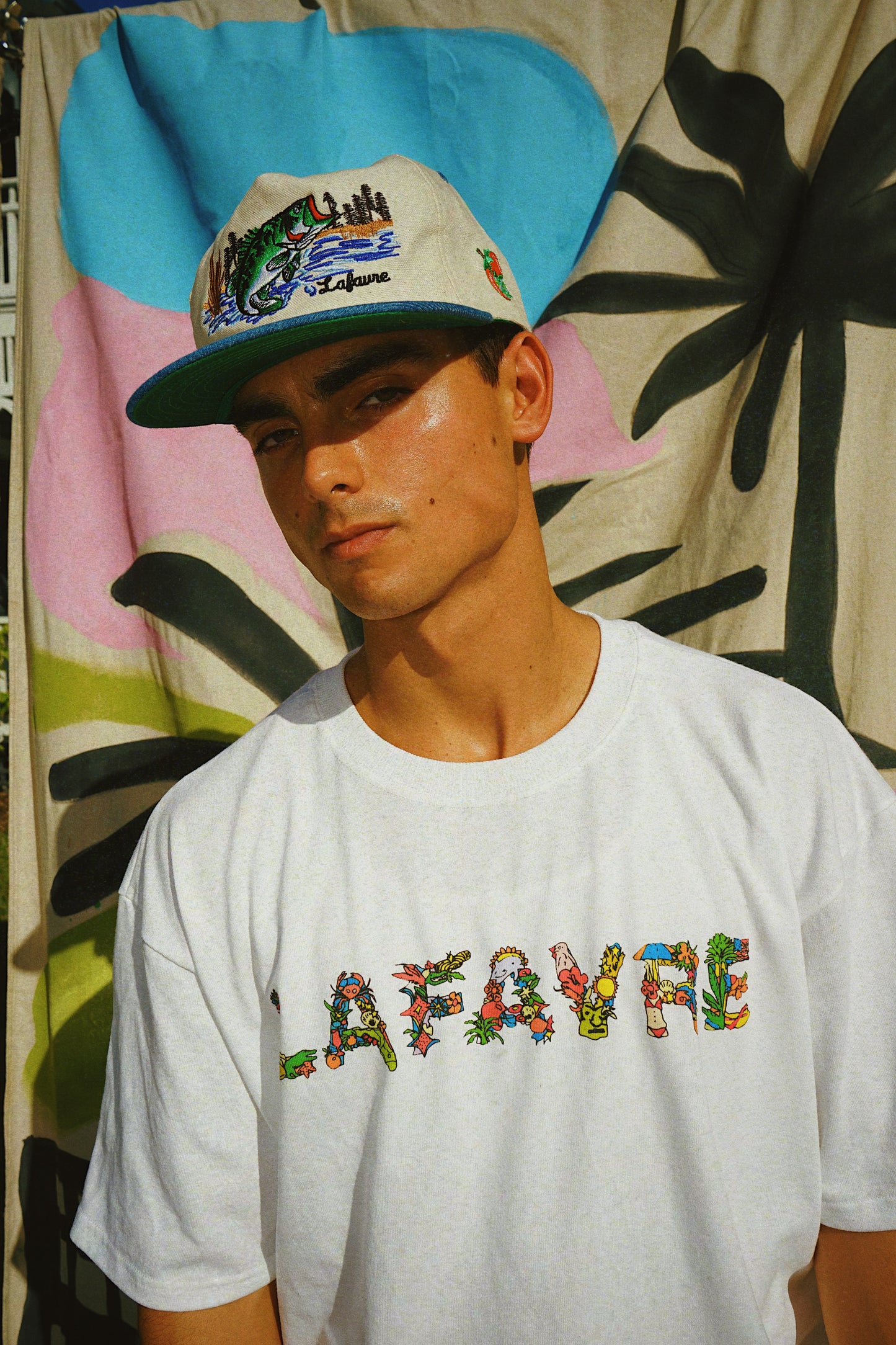 Person wearing a colorful cap and 'Lafavre' t-shirt against a patterned background