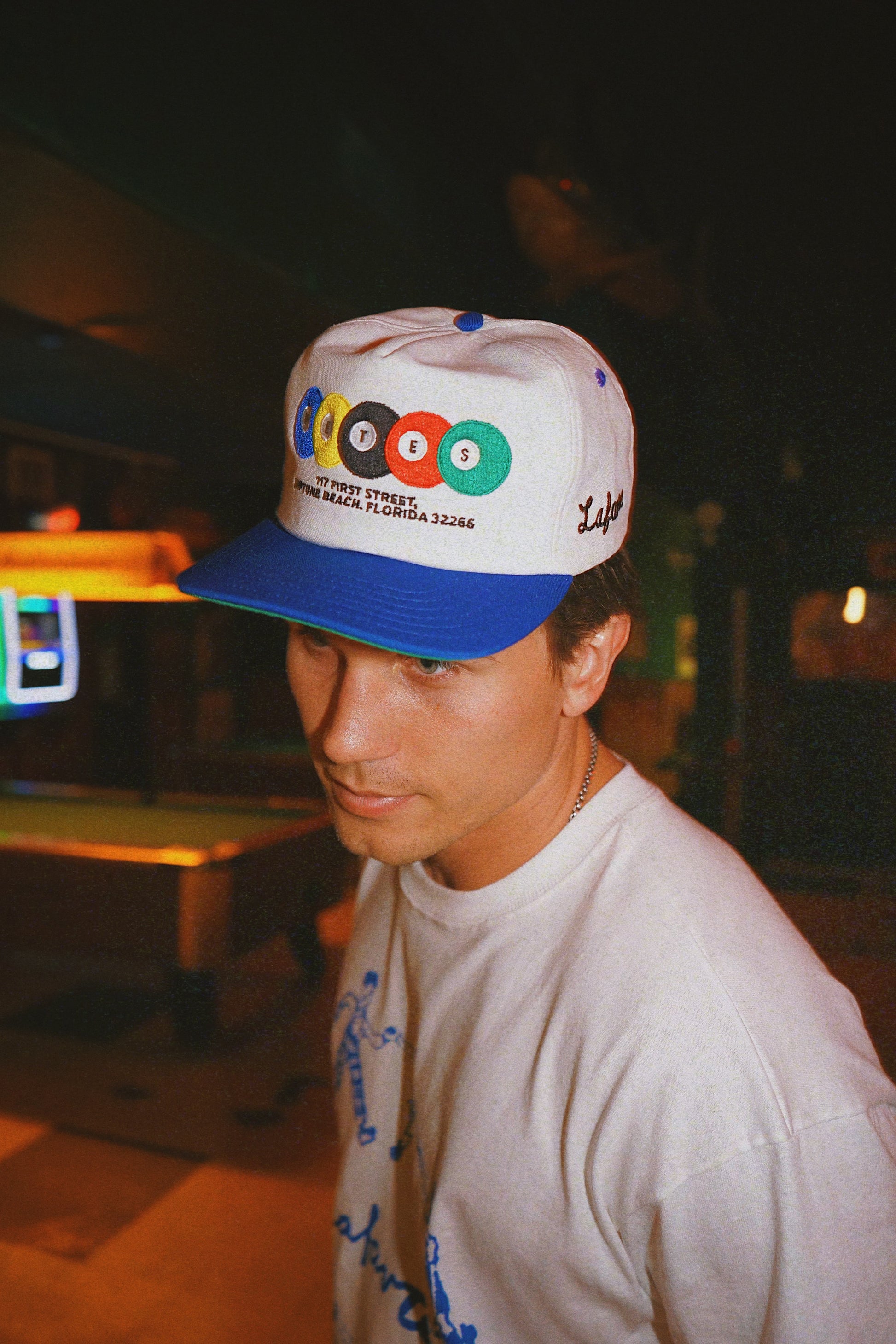 Man wearing a cap with colorful logos in an outdoor setting