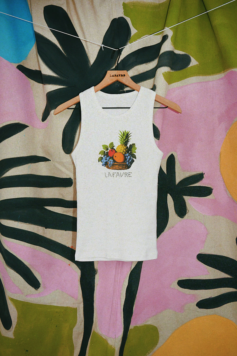 White tank top with fruit design on a hanger against a colorful floral background