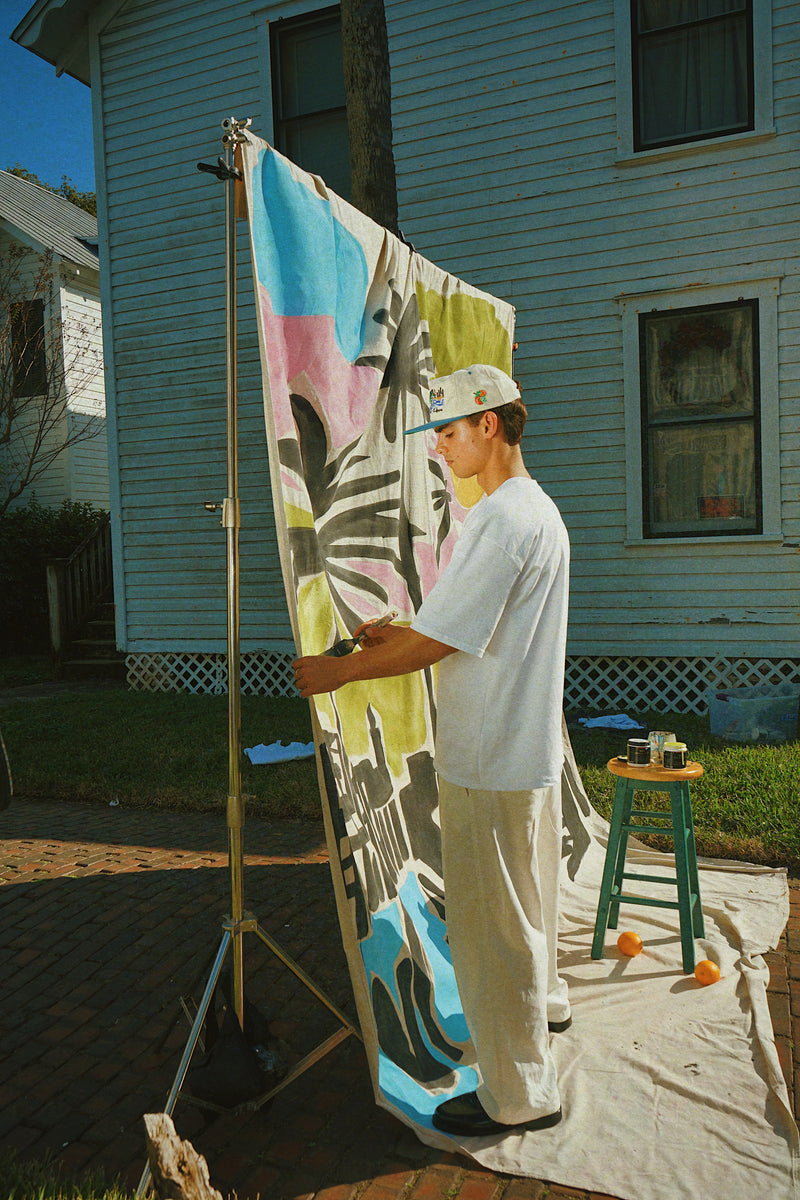 Person holding a colorful towel outdoors in front of a house
