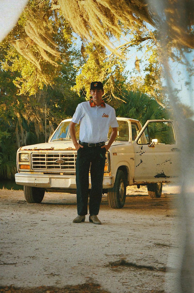 Man standing in front of a vintage truck with trees in the background